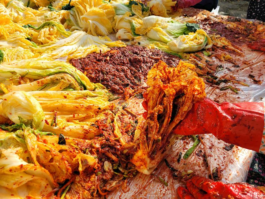 붉은 장갑을 끼고 배추에 양념을 버무리는 손